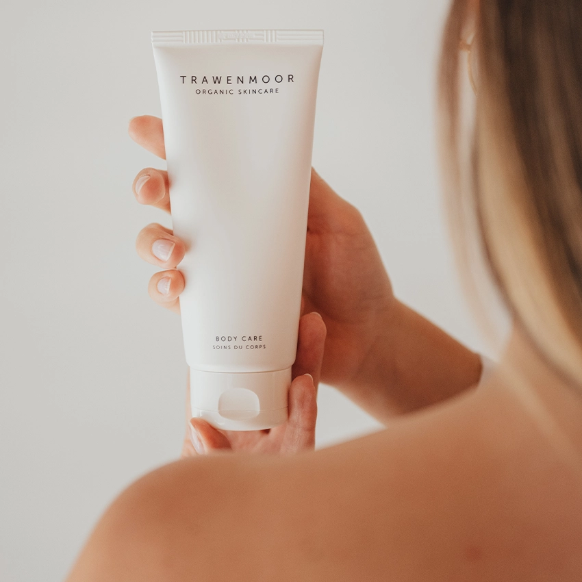 Woman holding Trawenmoor skin care tube in hand over shoulder